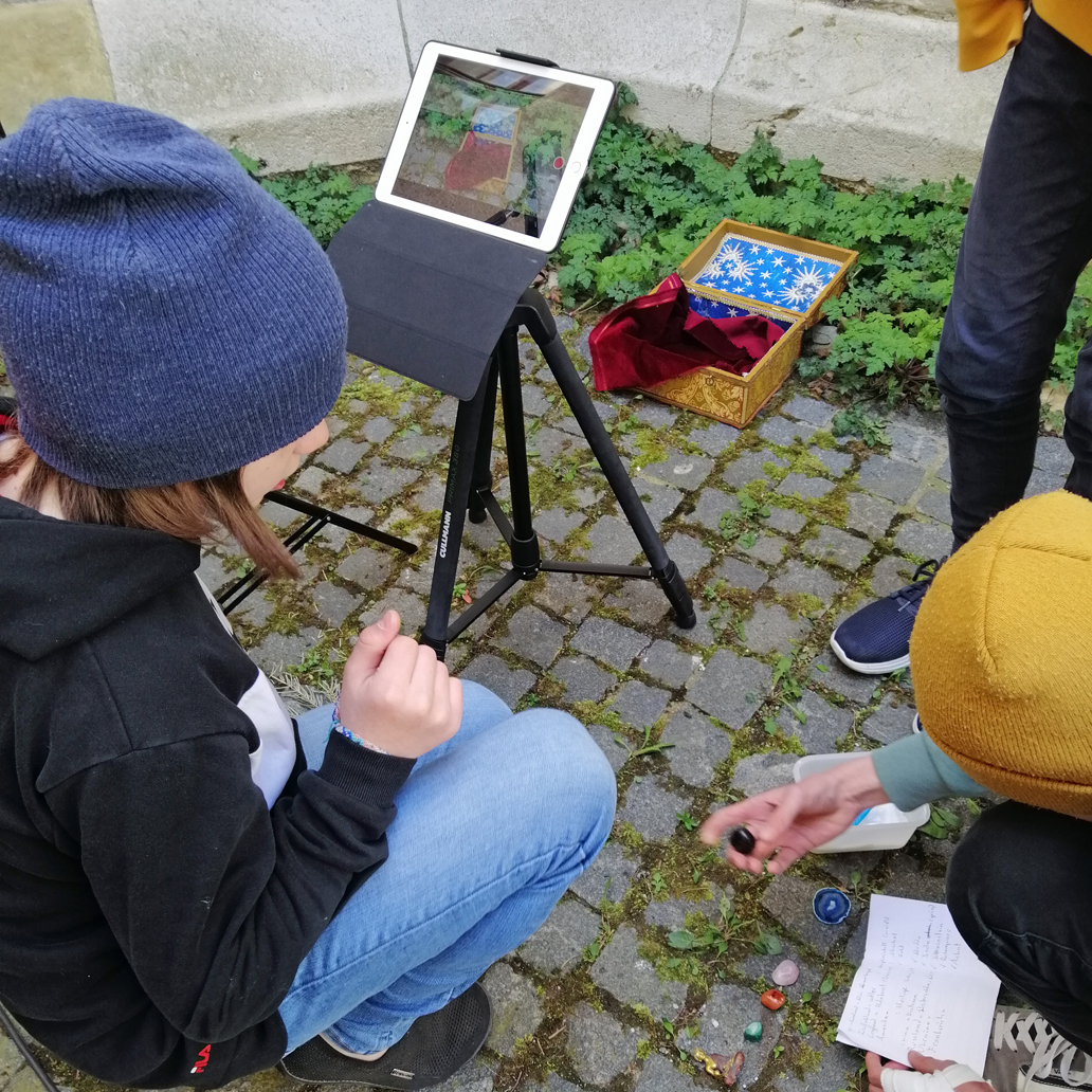 Jugendliche bereiten Edelsteine vor, die sie in einer goldblauen Schatzkiste filmen wollen